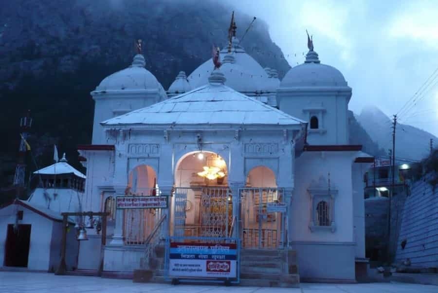Gangotri Temple illuminated during early morning hours, surrounded by misty Himalayan mountains in Uttarakhand