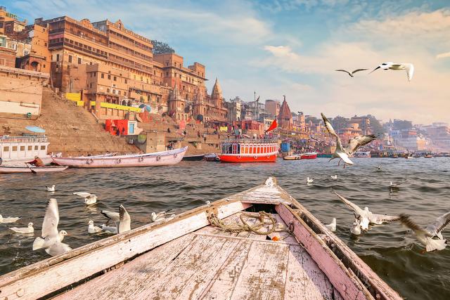 Riverfront view of Varanasi ghats along the River Ganga with temples, boats, and pilgrims