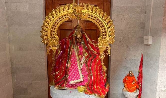Goddess Sharada idol dressed in red robes inside a modern shrine